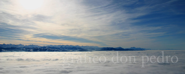 Nebelmeer und schneebedeckte Berge im Hintergrund